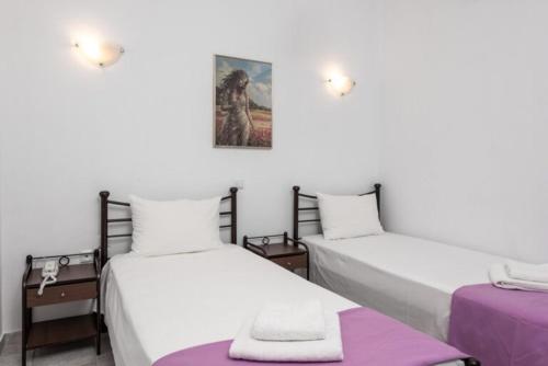 two beds in a room with white walls and purple sheets at Lithorama Granitsa mountain rooms in Granitsa