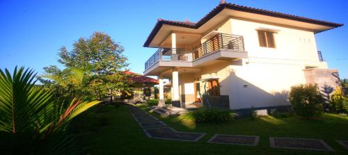 a large white house with a balcony and a yard at Yoga Homestay in Munduk