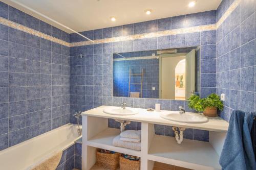 a blue tiled bathroom with two sinks and a tub at Bosc in Pals