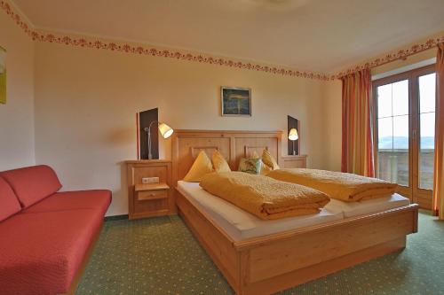 a bedroom with two beds and a red couch at Stiedlbauerhof in Seeham