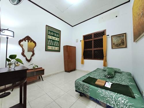 a bedroom with a bed and a desk and a piano at Ghanaya Guesthouse in Ngaglik