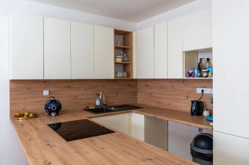 a kitchen with white cabinets and a wooden counter top at Tavba apartment in Česká Lípa