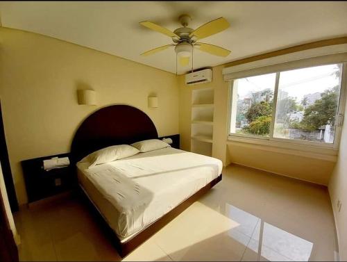 a bedroom with a bed with a ceiling fan and a window at Suite Club Deportivo in Acapulco