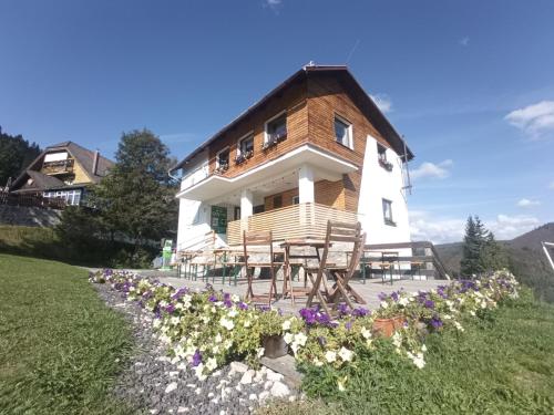 a house on a hill with flowers in front of it at Domček Horskej Služby in Liptovská Sielnica