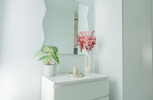a white bathroom with plants and a mirror at White Haven in Korinthos