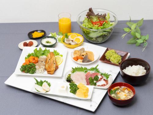 a table with several plates of food on it at Tabist Ishinomaki in Ishinomaki