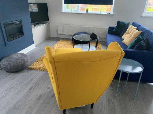 a living room with a yellow chair and a blue couch at Consett Gorgeous Two Bedroom Apartment in Consett