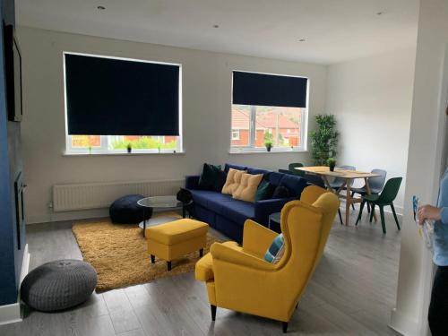 a living room with a blue couch and yellow chairs at Consett Gorgeous Two Bedroom Apartment in Consett