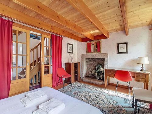 a bedroom with a bed and a desk and a fireplace at La petite maison du cap in Omonville-la-Rogue