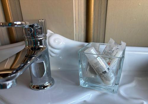 a glass vase filled with toothbrushes sitting on a sink at B&B Villa del Sole Relais in Agrigento