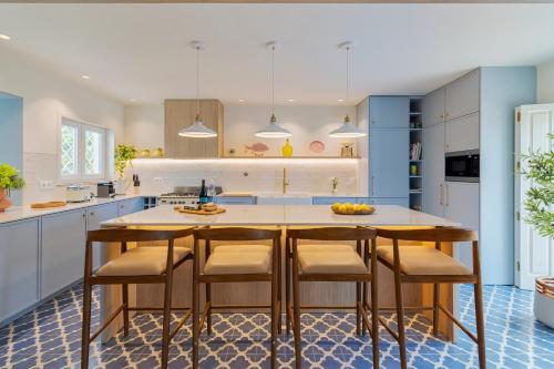a kitchen with blue cabinets and a table with chairs at Villa Vintage, By Home Match in Azeitao