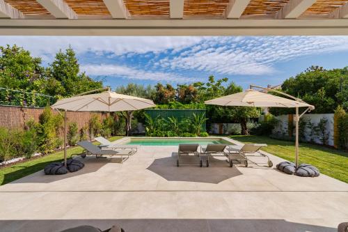 a patio with two umbrellas and chairs and a pool at Villa Vintage, By Home Match in Azeitao