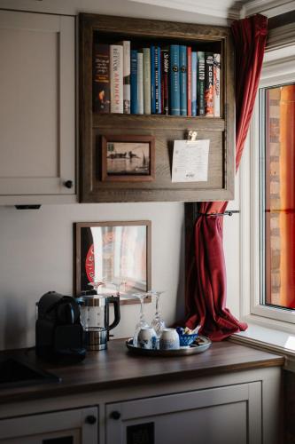 a kitchen counter with a book shelf with books at Hotell Gästis in Varberg