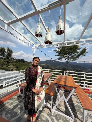 a man standing on a balcony with a table and lights at TheLocals HomeStay in Dhulikhel
