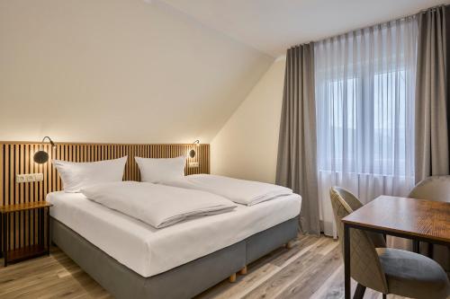 a hotel room with a bed and a desk and a window at Gästehaus am Weinberg in Oberheimbach