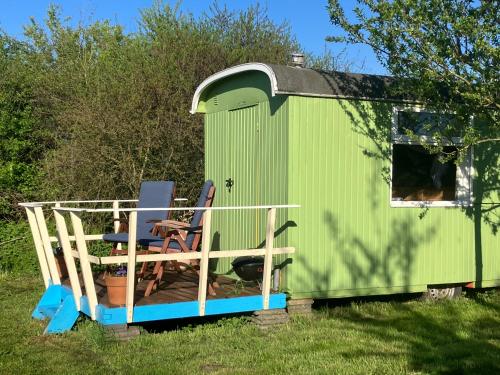 a green shed with two chairs and a table at Klein Garnwerd 9 in Garnwerd