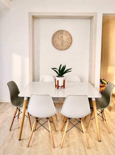 a dining room table and chairs with a clock on the wall at Dolphin View 34 in Langstrand