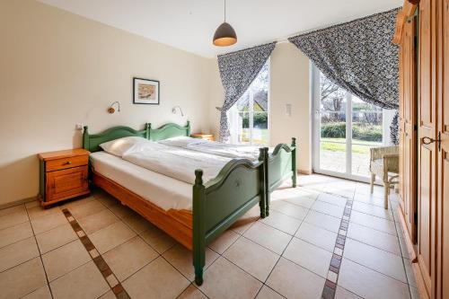 a bedroom with a green bed and a large window at Alte Büdnerei 1 Abeking-Haus in Althagen