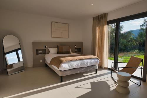 a bedroom with a bed and a large window at Villa Adeona in Zonza