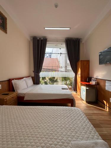 a hotel room with two beds and a flat screen tv at Hoa Cattleya Hotel in Da Lat