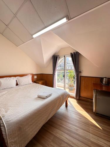 a bedroom with a large bed and a window at Hoa Cattleya Hotel in Da Lat