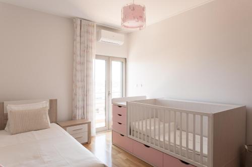 a white bedroom with a crib and a large window at Colinas Premium 3BR in Odivelas