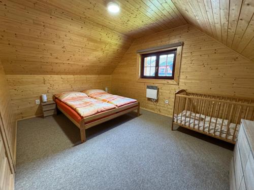 a bedroom in a wooden cabin with a bed and a window at Chalupa Nella II. in Velké Karlovice