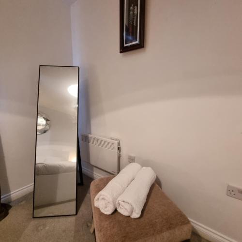a bathroom with a mirror and towels on a bench at Cozy Flat with Parking in Goodmayes