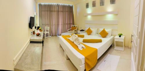 a bedroom with a large bed with yellow sheets at Beacon Beach Hotel Negombo in Negombo