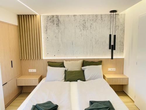 a bedroom with a bed with white sheets and green pillows at Harbor Hideaway Balatonfüred in Balatonfüred