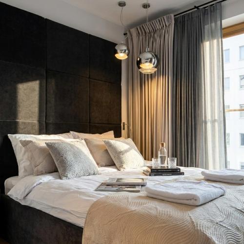 a bedroom with a large bed with a black headboard at Sky & Spa Luxury Residence in Warsaw