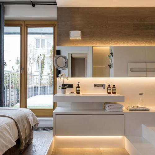 a bedroom with a bed and a sink and a mirror at Sky & Spa Luxury Residence in Warsaw