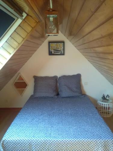 a bedroom with a blue bed in a attic at Maison à proximité des plages in Bénodet