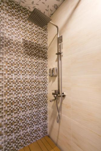 a shower in a bathroom with a tiled wall at Indochine Apartments in Ho Chi Minh City
