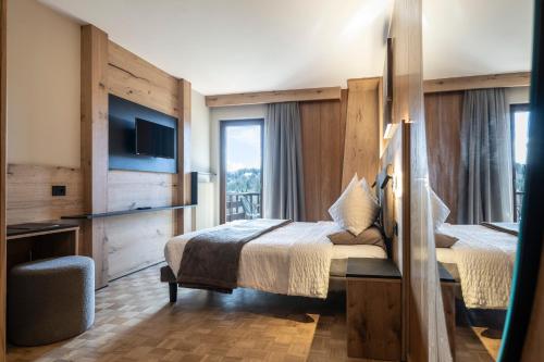 a hotel room with two beds and a television at Hotel Arcobaleno in Fai della Paganella