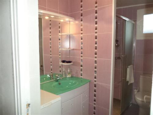 La salle de bains est pourvue d'un lavabo vert et d'une douche. dans l'établissement Maison de vacances à Créances, à Créances