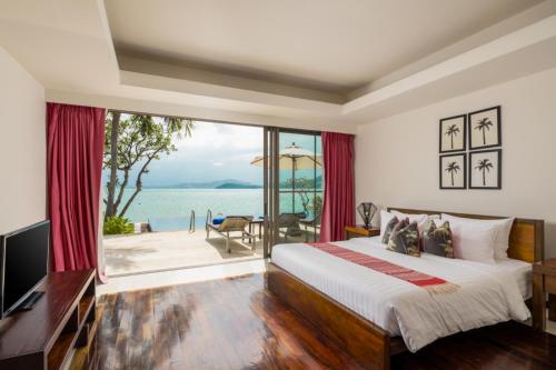 a bedroom with a bed and a view of the ocean at Dhevatara Residence Beachfront Villas in Mae Nam