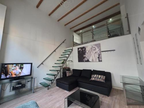 a living room with a black couch and a staircase at Urban Oasis - BIG stylish Apartment in Schiedam