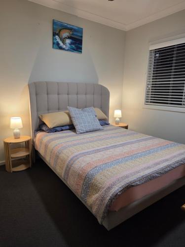 a bedroom with a large bed with two lamps at Quiet Homestay Ulladulla in Ulladulla