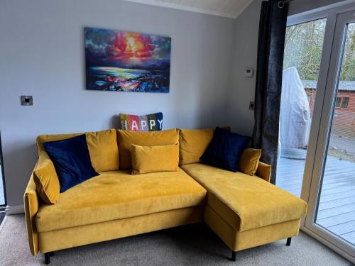 a yellow couch with blue pillows in a living room at V+B Hygge in Windermere