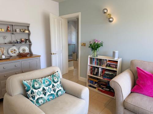 a living room with two chairs and a book shelf at Old Hunstanton luxury by the sea in Hunstanton