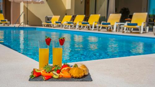 a tray of fruit and juice next to a swimming pool at Villa Bahamas - Jacuzzi e piscina aquecível em Armação de Pêra in Armação de Pêra
