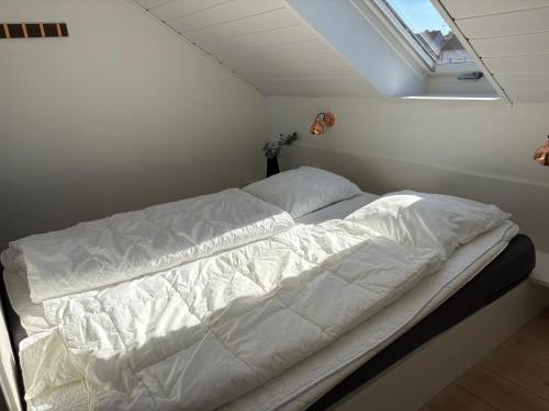 a white bed in a room with a window at Vigen ferielejligheder in Ebeltoft