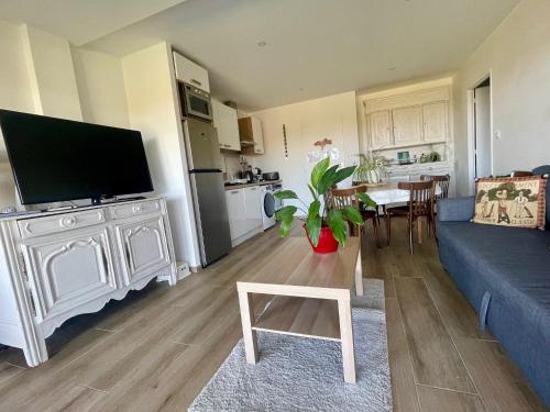 a living room with a blue couch and a kitchen at Perle de vue in Glaine-Montaigut