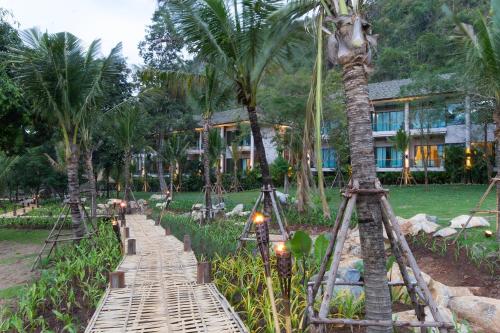 a wooden bridge in front of a resort with palm trees at The Series Resort Khaoyai in Phayayen