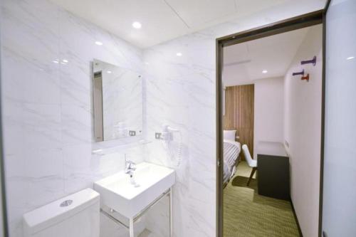 a white bathroom with a sink and a mirror at 西門大飯店 Ximen Hotel in Taipei