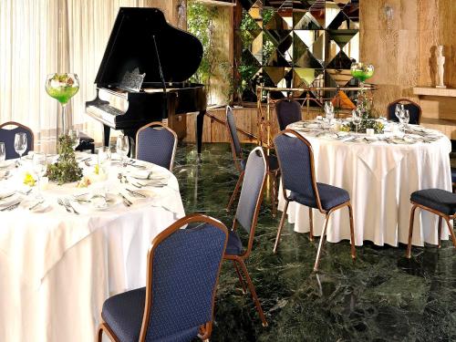 a dining room with two tables and a piano at Savoy Hotel in Piraeus