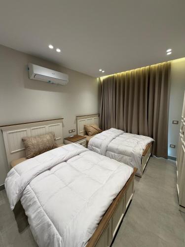 a bedroom with two beds and a window at Chic Stays Modern 3BR in Mountain View ICITY in 6th Of October