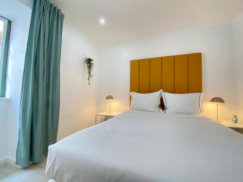 a bedroom with a large white bed and green curtains at Vibrant Setúbal II, By Home Match in Setúbal