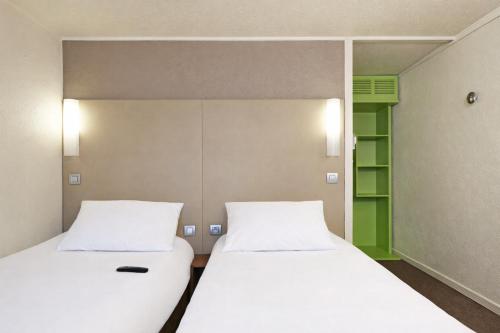 a pair of beds in a room with a mirror at Campanile Lens in Lens